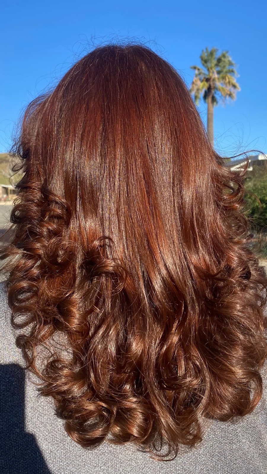 Long copper-red hair color finished with big bouncy curls